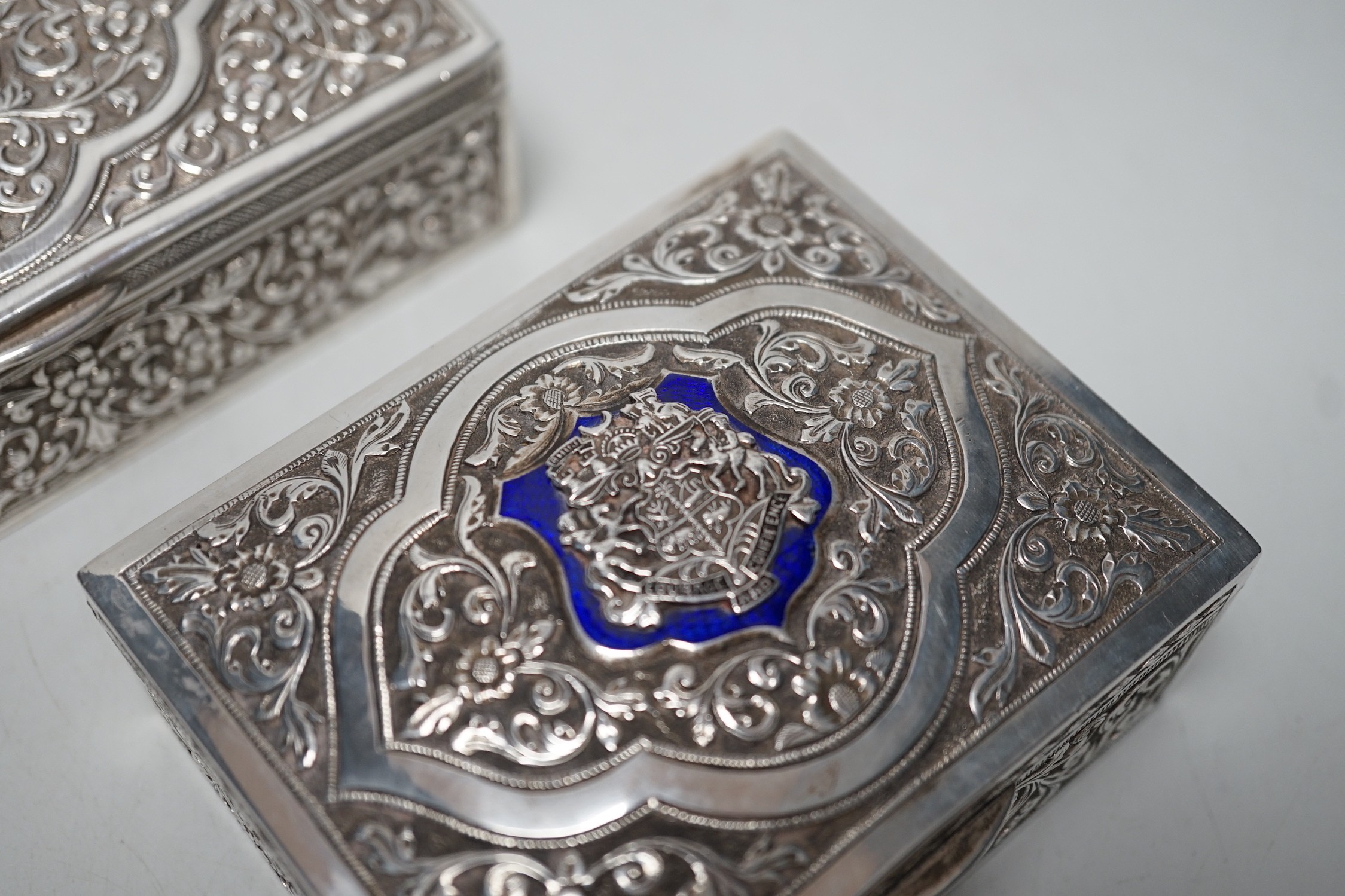 Two early 20th century Indian embossed white metal rectangular boxes, both applied with the enamelled rest of the Bhuj Kutch Gujarat, largest 14.2cm